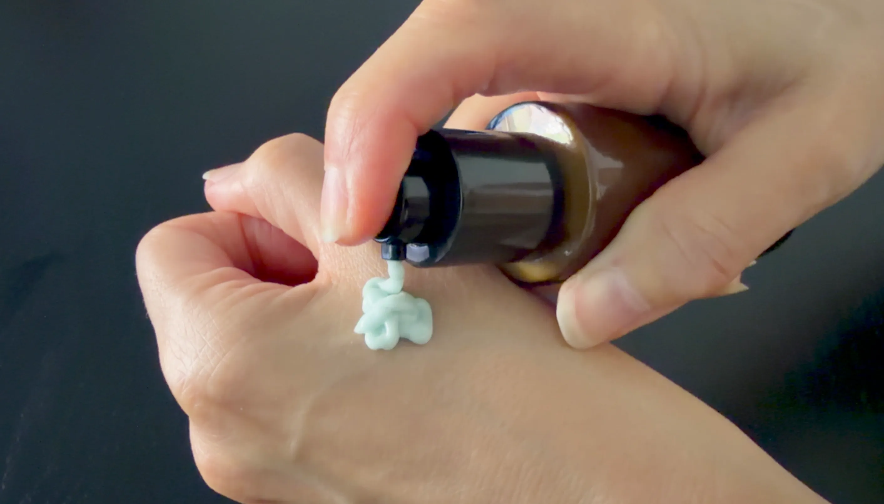 A soft blue-green blue tansy face cream applied to the back of a hand